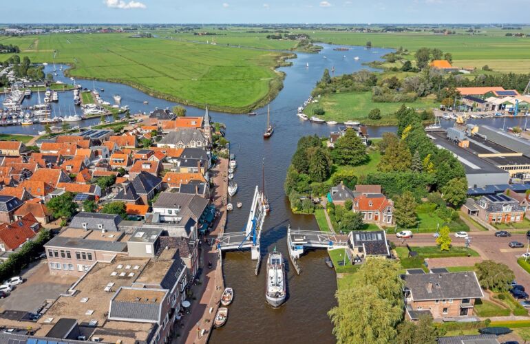 Luchtfoto van sluis, opengaande brug en historische huizen